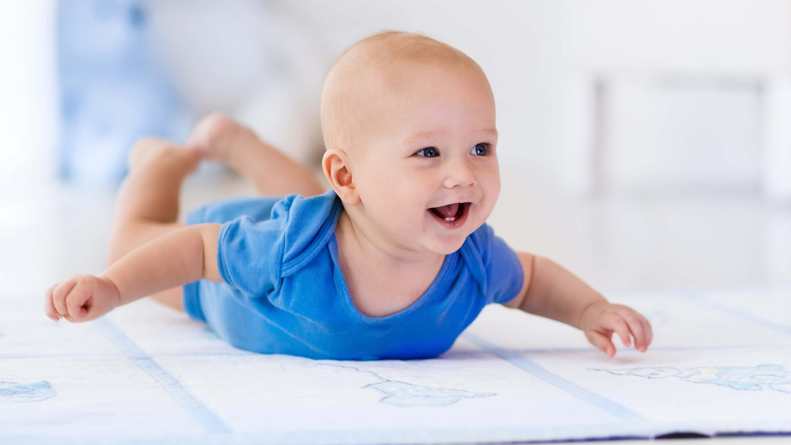 Baby in blue babygrow on a mat