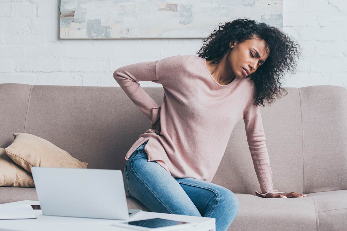 Young lady on sofa suffering from back pain